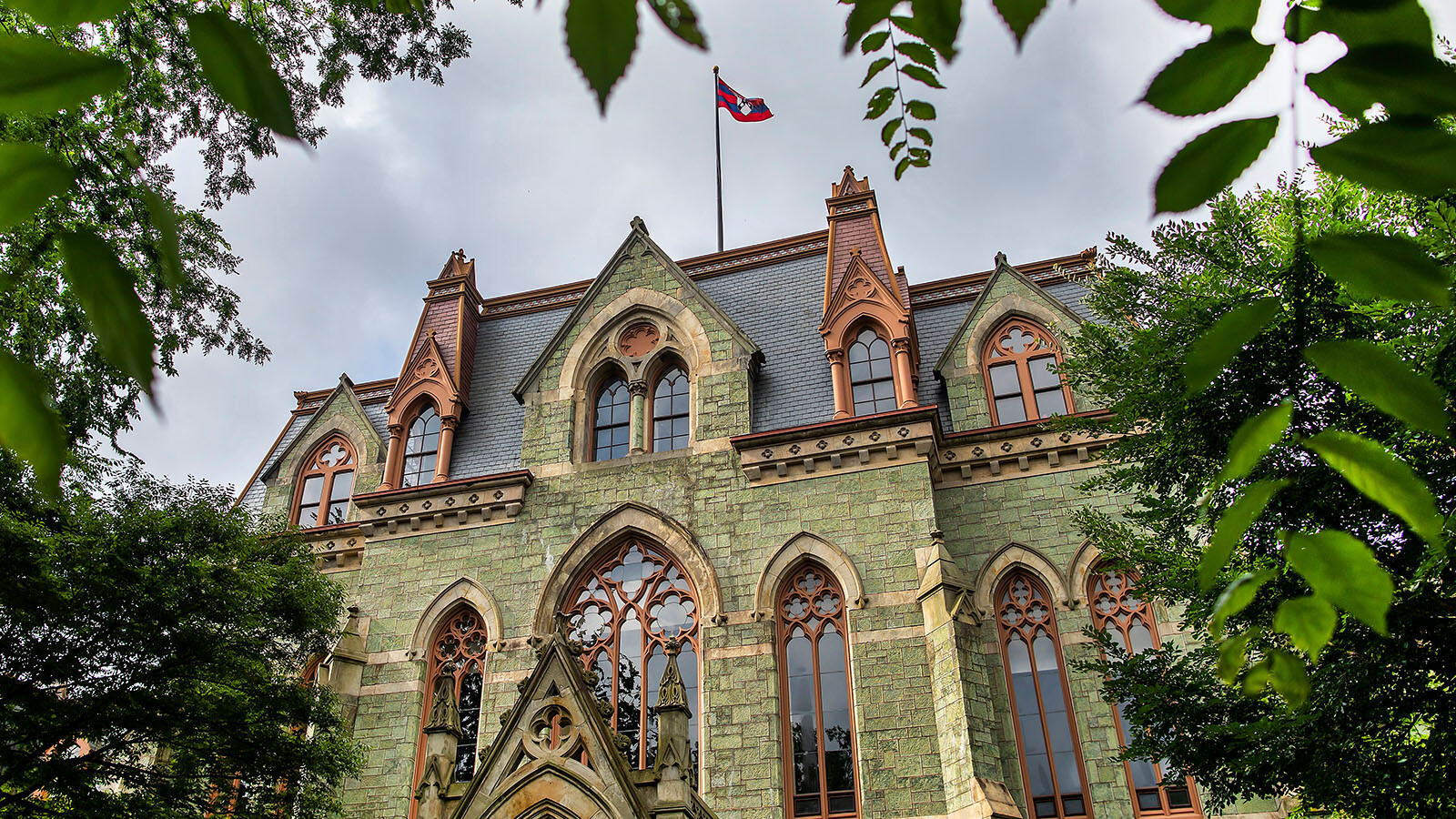 The collegiate gthic style facade of College Hall framed by mature trees